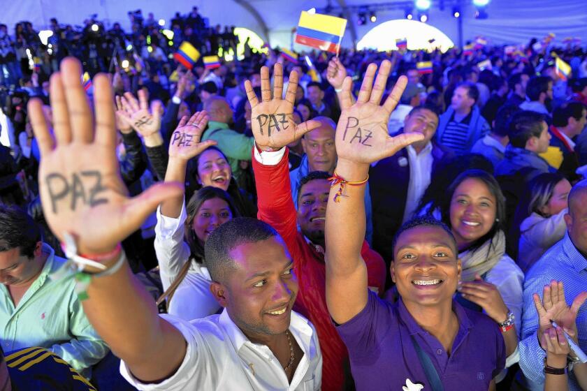 Supporters of Colombian President Juan Manuel Santos celebrate his reelection victory with the word "peace" written on their palms.