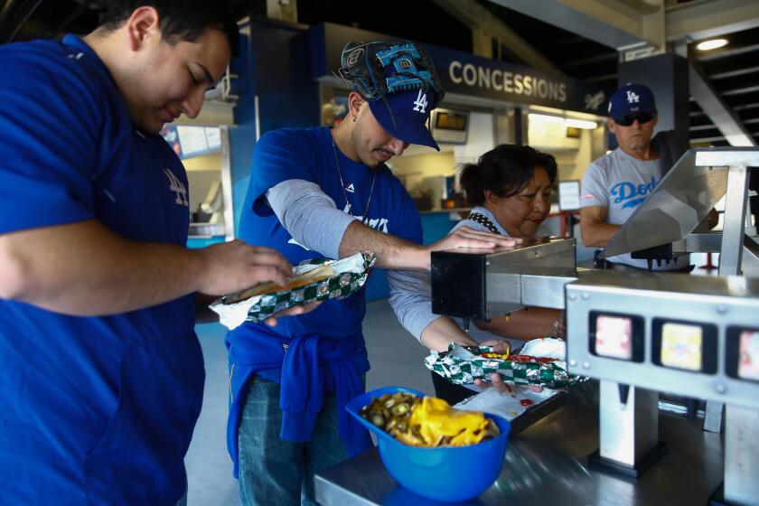 LOS ANGELES, CALIF. - MAY 27: Eric and Steve Soto put condiments on their Dodger Dogs at Dodger Stadium on Monday, May 27, 2019 in Los Angeles, Calif. (Kent Nishimura / Los Angeles Times)