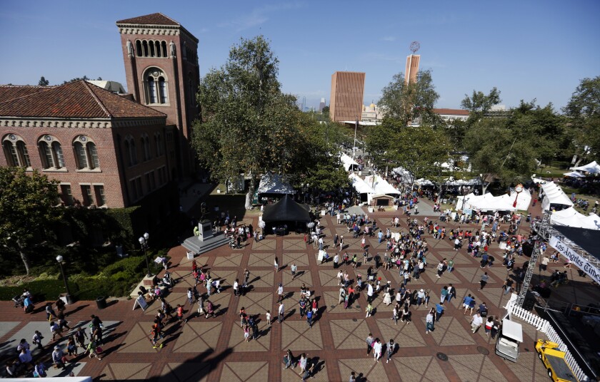 A crowd of people walks through the USC campus.   