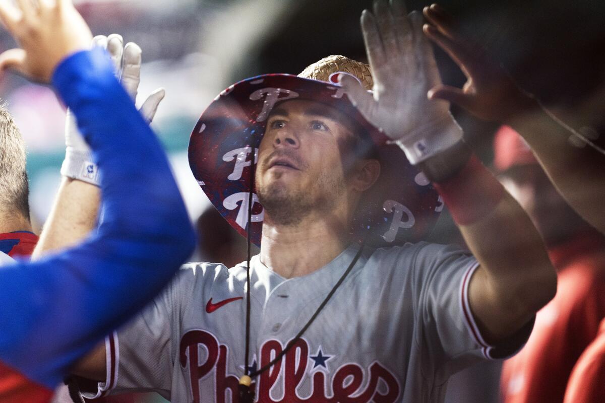 Philadelphia Phillies' J.T. Realmuto celebrates with teammates in their dugout after scoring a home run during the seventh inning of a baseball game against the Washington Nationals in Washington, Tuesday, Aug. 3, 2021. (AP Photo/Manuel Balce Ceneta)