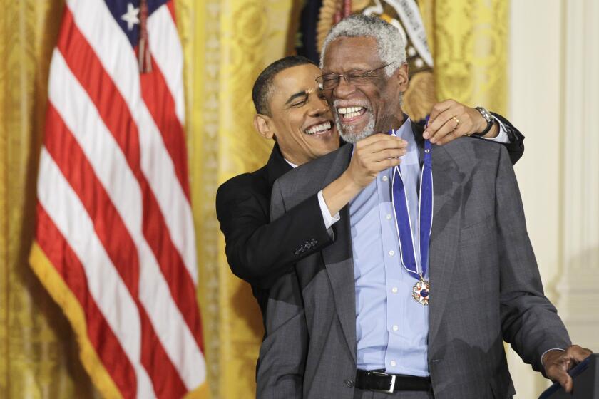 President Barack Obama reaches up to present a 2010 Presidential Medal of Freedom to basketball hall of fame member, former Boston Celtics coach and captain Bill Russell, Tuesday, Feb. 15, 2011, during a ceremony in the East Room of the White House in Washington.(AP Photo/Charles Dharapak)