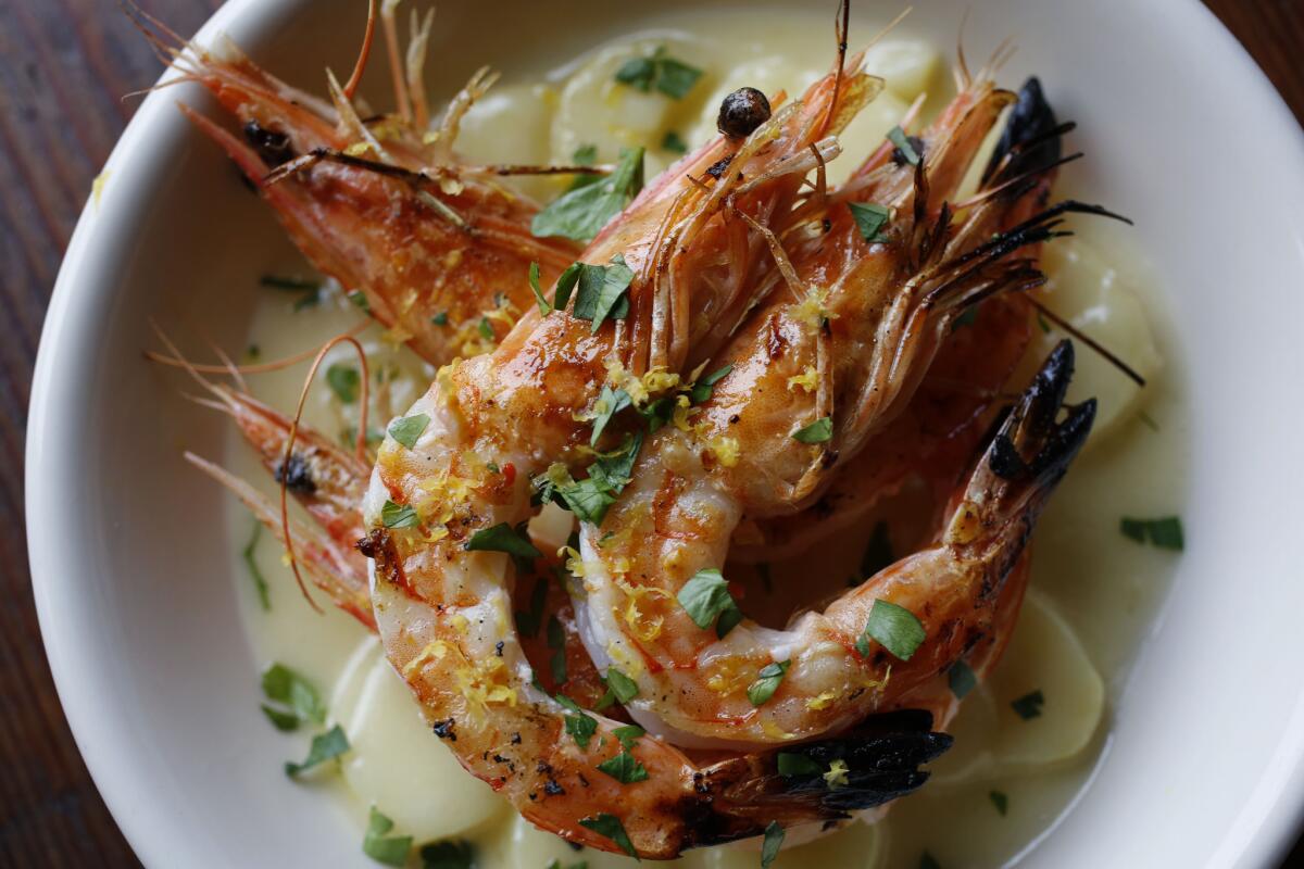 Grilled Australian blue prawns are served atop garlicky buttered potatoes at Odys + Penelope