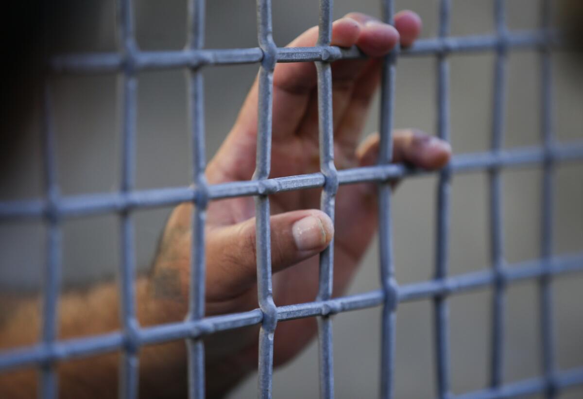 A condemned prisoner touches the mesh fence in the exercise yard during a media tour at San Quentin State Prison.