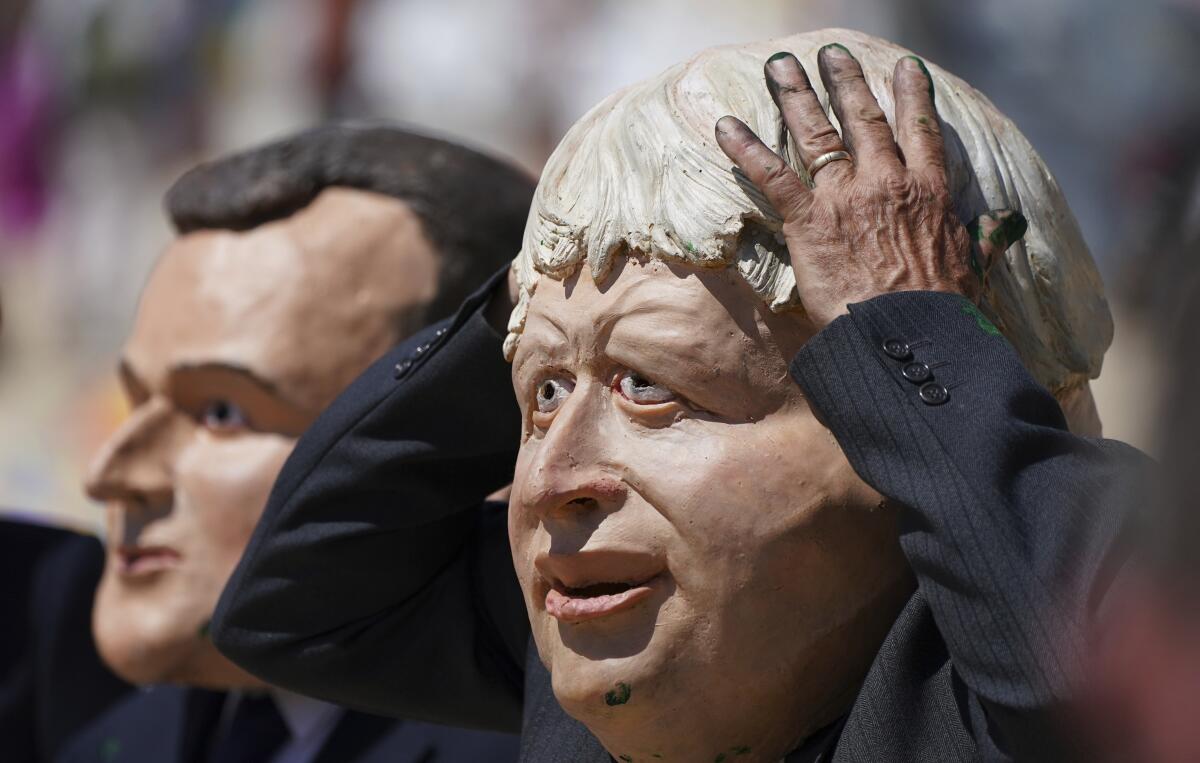 Protestors wearing giant heads portraying G7 leaders British Prime Minister Boris Johnson, right, and French President Emmanuel Macron participate in a demonstration on a beach outside the G7 meeting in St. Ives, Cornwall, England, Sunday, June 13, 2021. Leaders of the G7 wrap up three days of meetings in Carbis Bay Sunday, in which they discussed such topics as COVID-19, climate, foreign policy and the economy. (AP Photo/Jon Super)