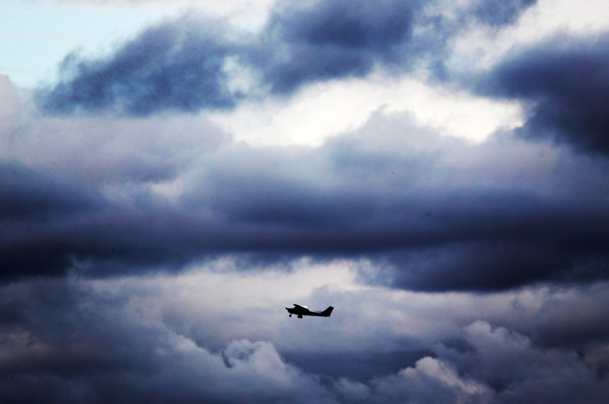 A plane takes off amid dark, heavy clouds.