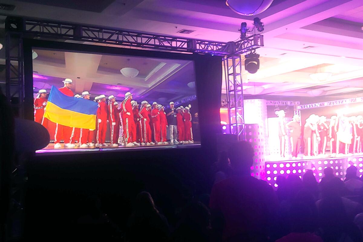 A dance crew in red tracksuits holds up a Ukrainian flag