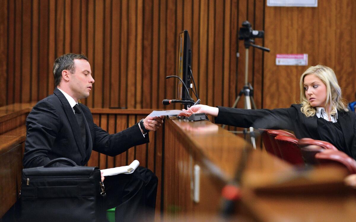 Oscar Pistorius hands a note to a member of his legal team at the High Court in Pretoria, South Africa.