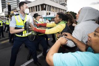 Police and protesters clash in Wellington, New Zealand, Tuesday, Feb. 22, 2022, as police tightened a cordon around a protest convoy that has been camped outside Parliament for two weeks. The protesters, who oppose coronavirus vaccine mandates and were inspired by similar protests in Canada, appear fairly well organized after trucking in portable toilets, crates of donated food, and bales of straw to lay down when the grass turned to mud. (George Heard/New Zealand Herald via AP)