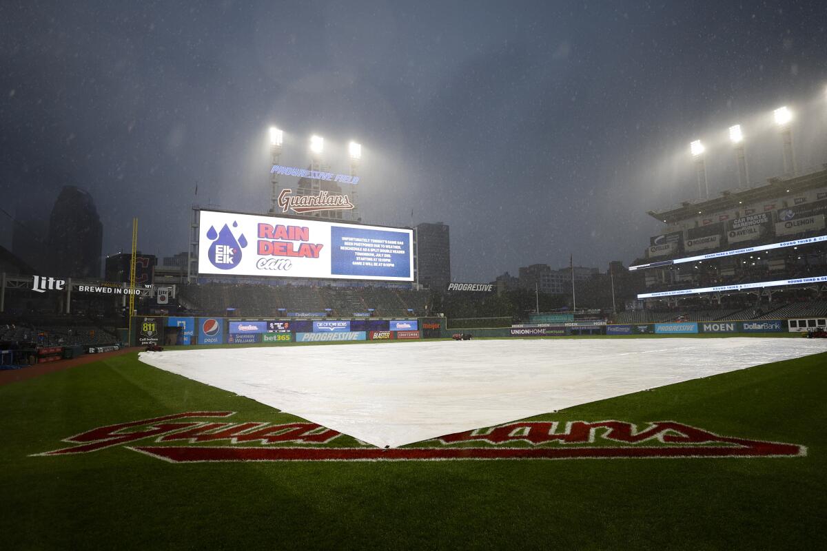 The tarp covers the infield as rain falls before a scheduled baseball game between the New York Yankees and the Cleveland Guardians on Friday, July 1, 2022, in Cleveland. The game was postponed due to inclement weather. (AP Photo/Ron Schwane)