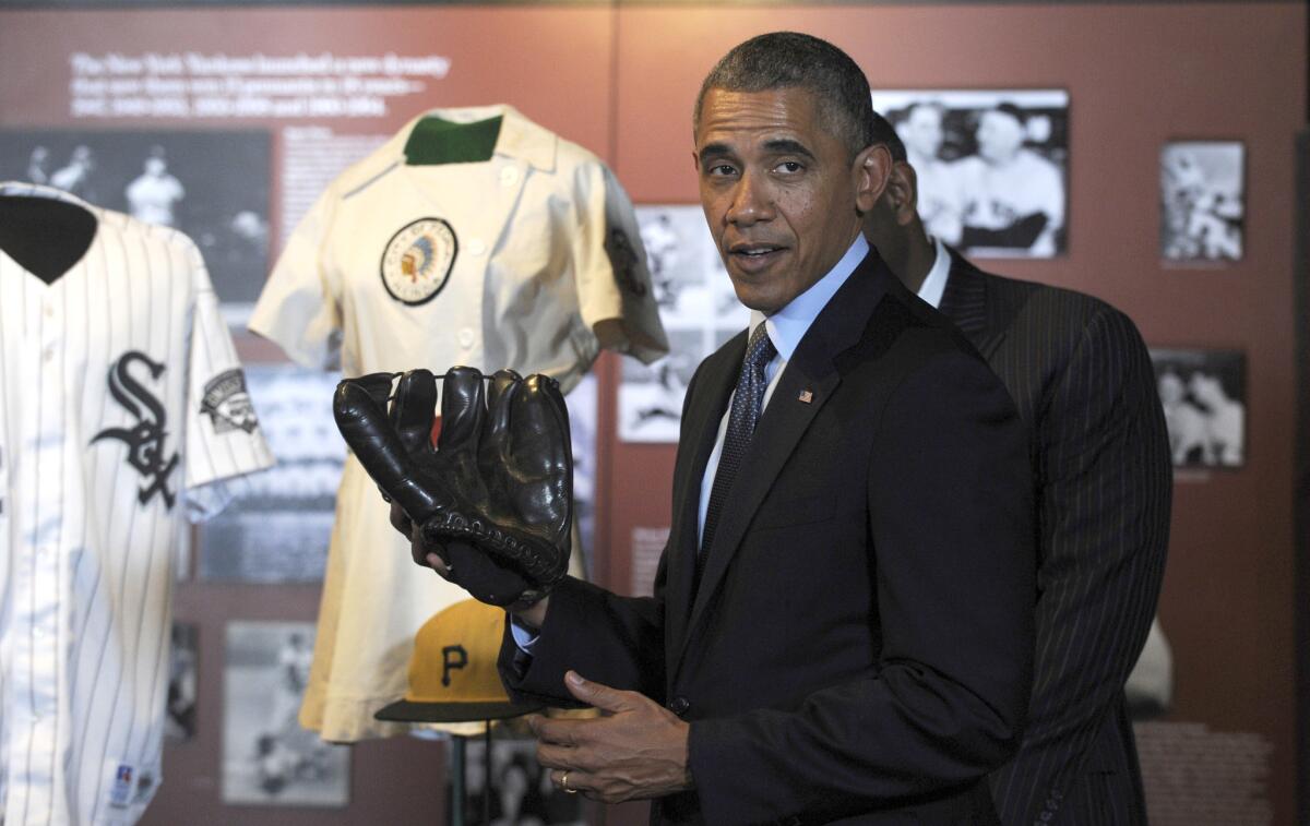 President Obama holds Joe DiMaggio's glove during a tour of the Baseball Hall of Fame in Cooperstown, N.Y.