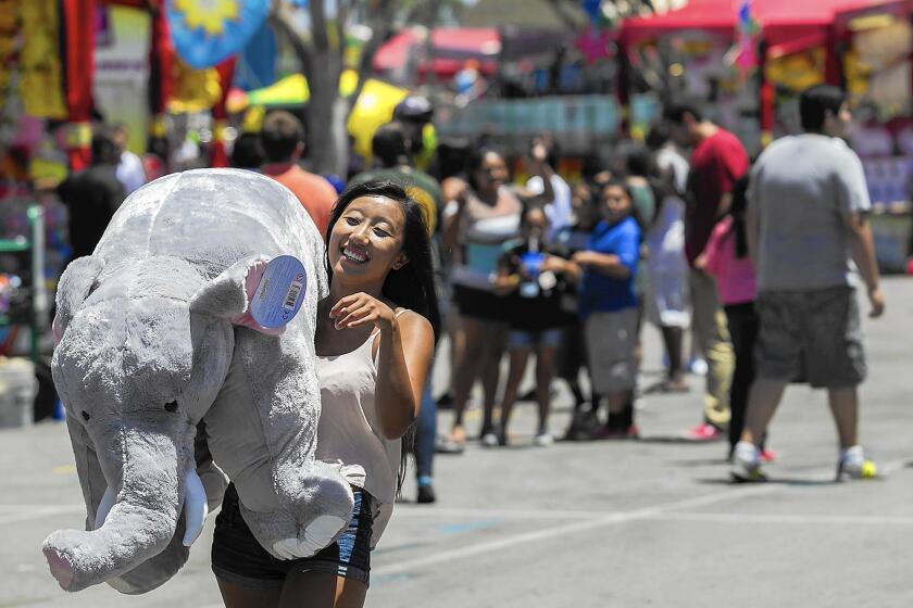 In this 2014 photo, Sia Keys carries a giant stuffed elephant that she won in the ring toss during the Orange County Fair.