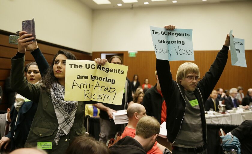 Students hold up protest signs at the end of a public comment period during a University of California Board of Regents meeting Wednesday, March 23, 2016, in San Francisco. A committee of the University of California's governing board unanimously approved a statement Wednesday that cites anti-Semitism as a form of intolerance that campus leaders have a duty to challenge. The committee of the university's Board of Regents voted to send what is being called a "Statement of Principles Against Intolerance" on to the full board for final consideration on Thursday. (AP Photo/Eric Risberg)