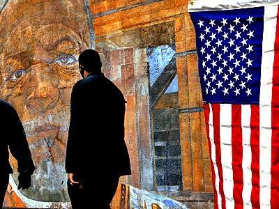 Voters make their way past a flag and a mural at the Watts Towers Arts Center, which served as a polling place. Art curator Cecil Ferguson is depicted in the mural.