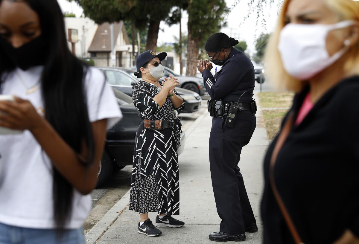 A woman in police uniform speaks to another woman on a sidewalk