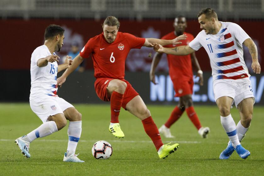 Canada midfielder Samuel Piette (6) tries to fend off U.S. midfielder Cristian Roldan (15) and forward Jordan Morris (11) during the first half of a CONCACAF Nations League soccer match Tuesday, Oct. 15, 2019, in Toronto. (Cole Burston/The Canadian Press via AP)