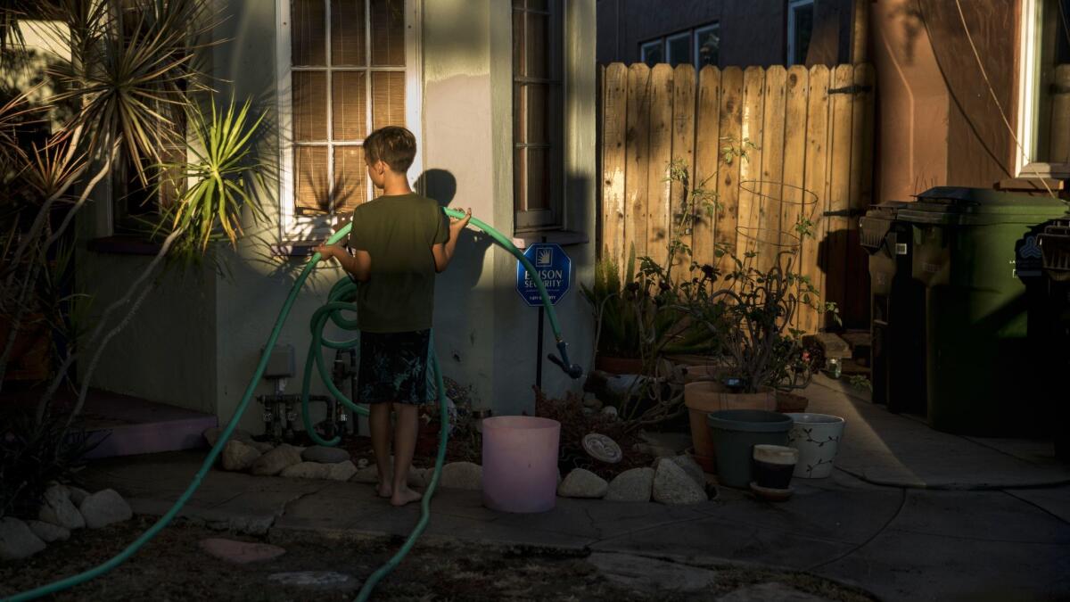 The Schwartz family got a warning from the city to paint its redwood gate or pay $660. Above Caden Schwartz, 9, puts away a garden hose after washing his mother's car.