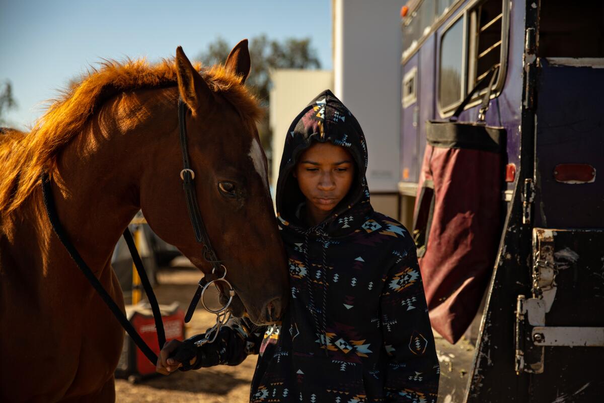 Sylvester Miller of Stockton stands by his horse at a reservoir in Oakdale, Calif.