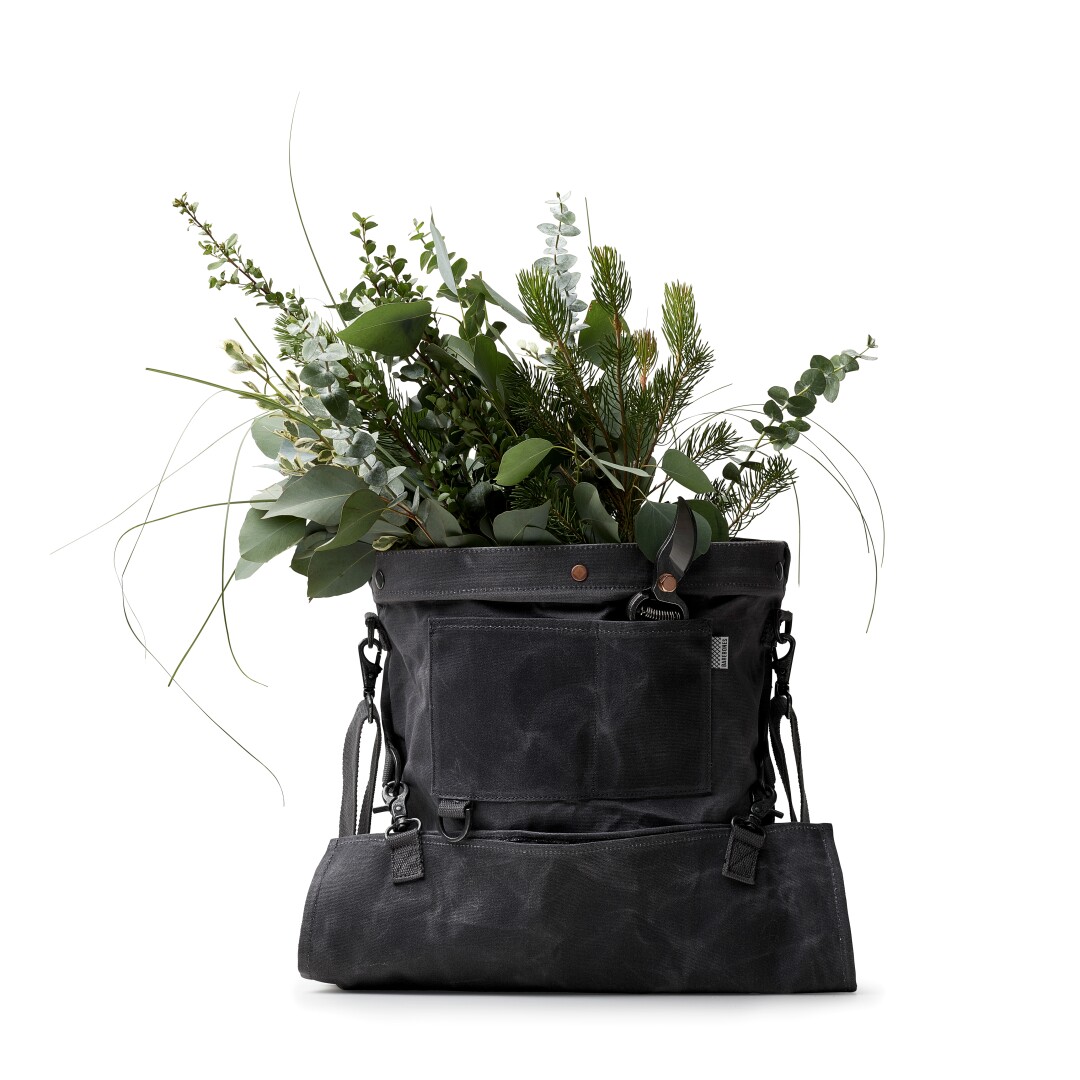 A bag with flowers and other plants poking out of the top.