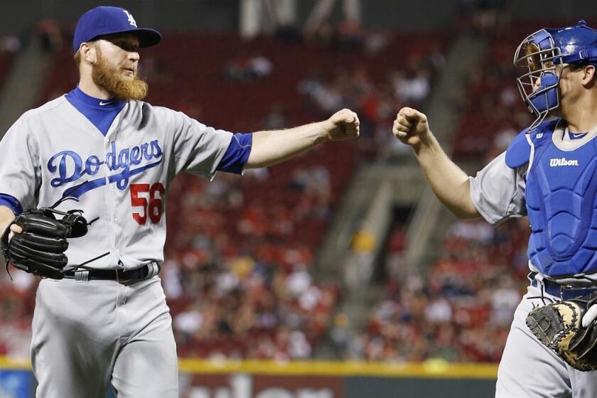 Dodgers relief pitcher J.P. Howell is congratulated by catcher Tim Federowicz after ending the seventh inning with a double play against the Reds on Monday night.