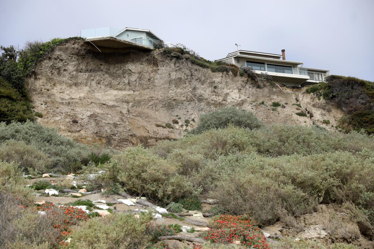 Two homes atop an eroded bluff that threatens to undermine them.