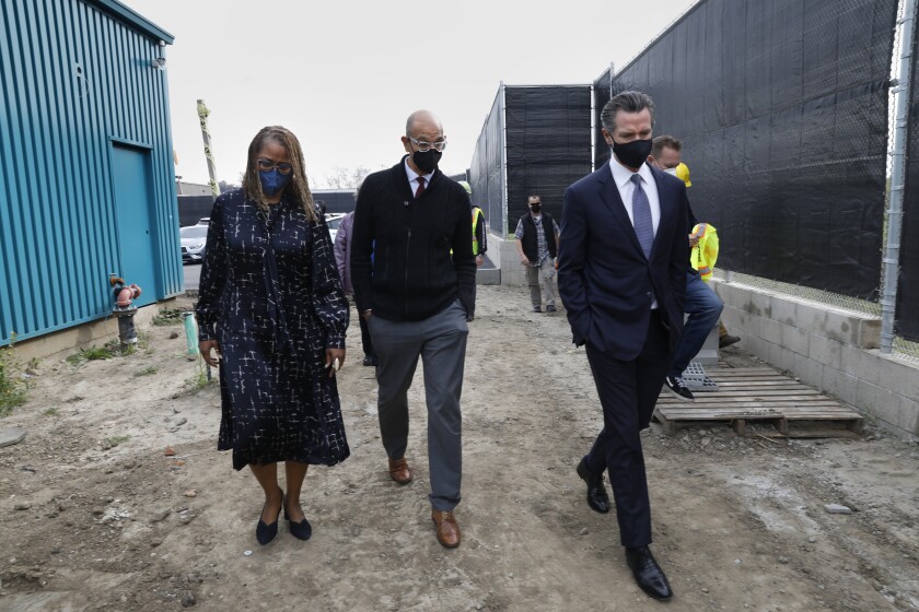 Three people wearing masks walk side by side.