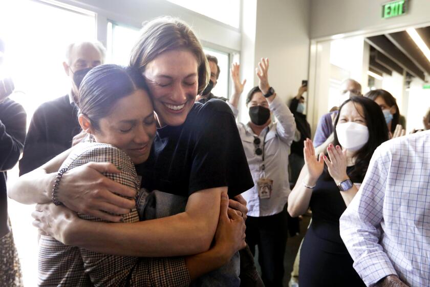EL SEGUNDO, CA - MAY 8, 2023 - Los Angeles Times photographer Christina House, left, is hugged by former LA Times videographer Claire Collins after House won the Pulitzer Prize for Feature Photography at the Los Angeles Times in El Segundo on May 8, 2023. House won for her photoessay on the life of a pregnant 22-year-old woman living on the street in a tent and her struggle to raise her child. Collins shot the video. (Genaro Molina / Los Angeles Times)