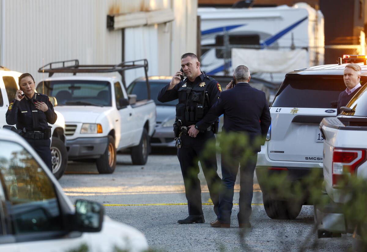 Law enforcement officers stand next to vehicles