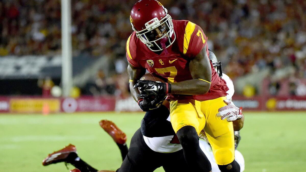 Trojans receiver Steven Mitchell breaks a tackle by Arkansas State defensive back Cody Brown to score a touchdown in the season opener.