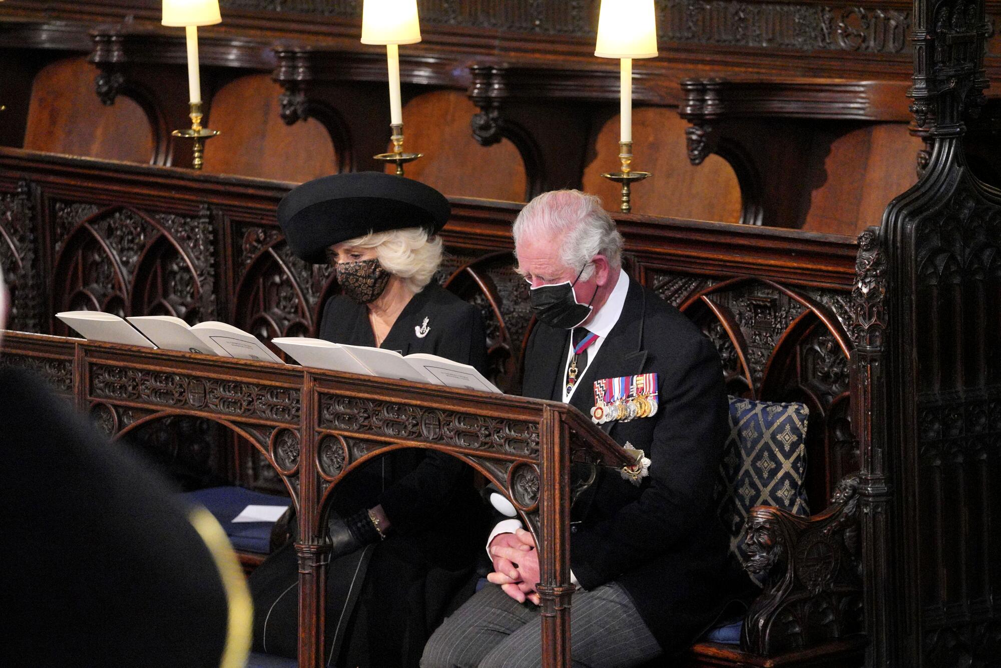 Prince Charles and Camilla sit in masks in St. George's Chapel.