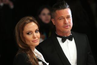 Actors Angelina Jolie and Brad Pitt pose for photographers in black tuxedos