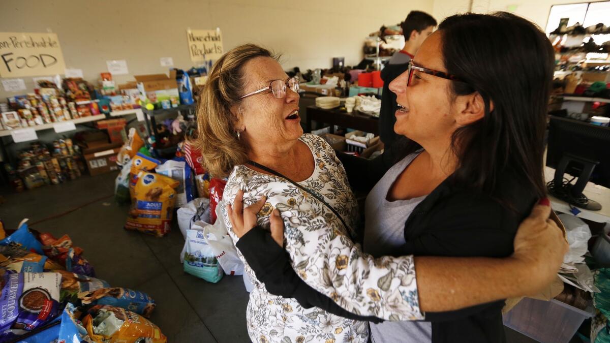 Jenn Kurtz, right, an organizer of the Las Virgenes Fire Relief Center in Agoura Hills, hugs volunteer Deb Stein as they help people who have lost their homes in the Woolsey fire.