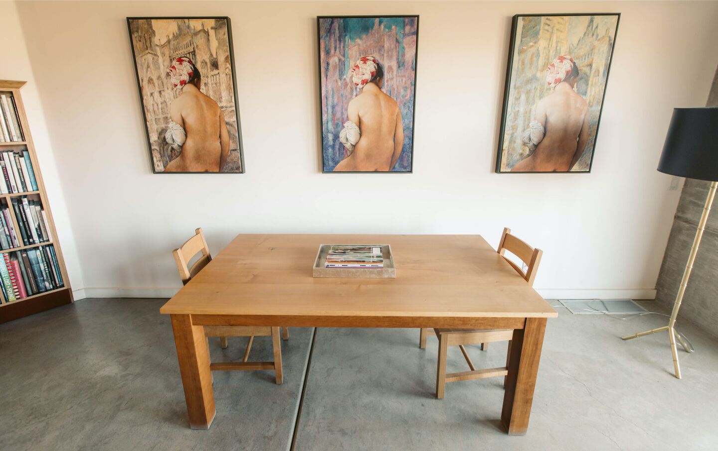 A table for two sits against a white wall with three works of art.