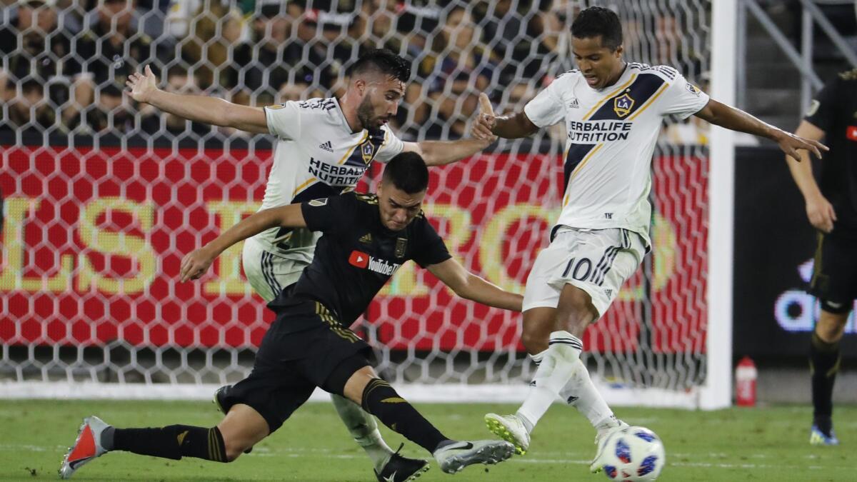 Galaxy midfielder Romain Alessandrini, left, and forward Giovani dos Santos, right, battle LAFC midfielder Eduard Atuesta for control of the ball in the second half at the Banc of California Stadium on July 26, 2018. The game ended tied 2-2.