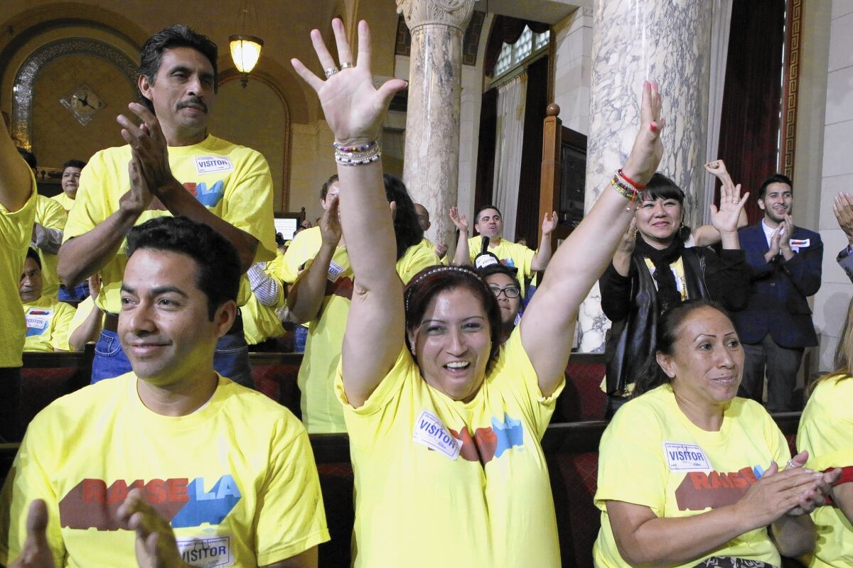 Blanca Aldana raises her hands in victory after the Los Angeles City Council approved a $15.37-per-hour minimum wage for workers at big hotels. The measure will be put to a second procedural vote next week.