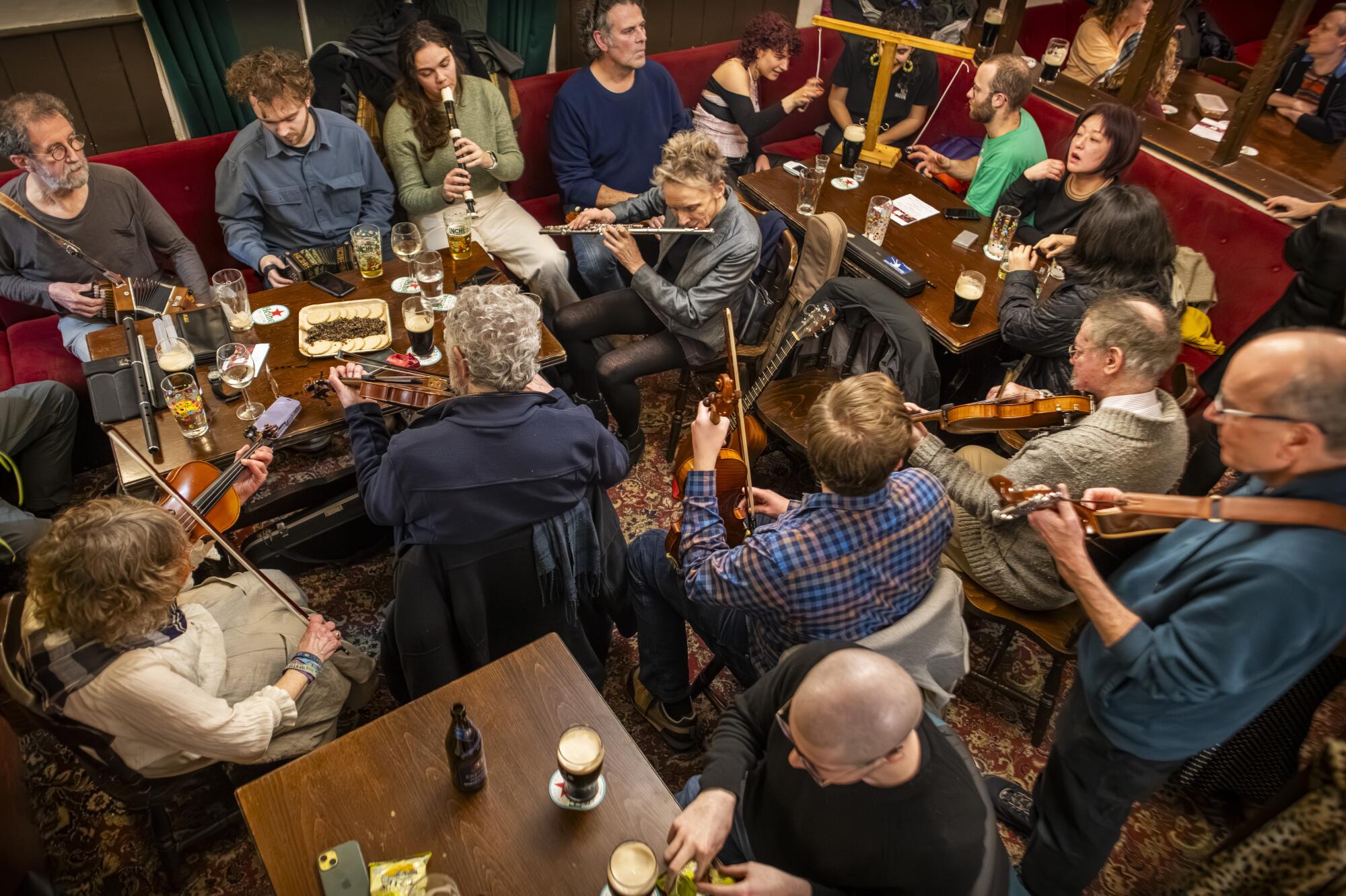 Musicians play around a table in a crowded pub 
