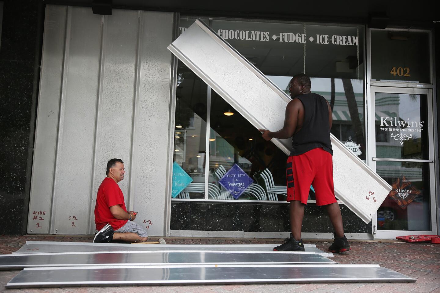Jason Brock (left) and Kevin Hunter put up hurricane shutters in front of a business as Hurricane Matthew approaches Delray Beach on Oct. 6, 2016.