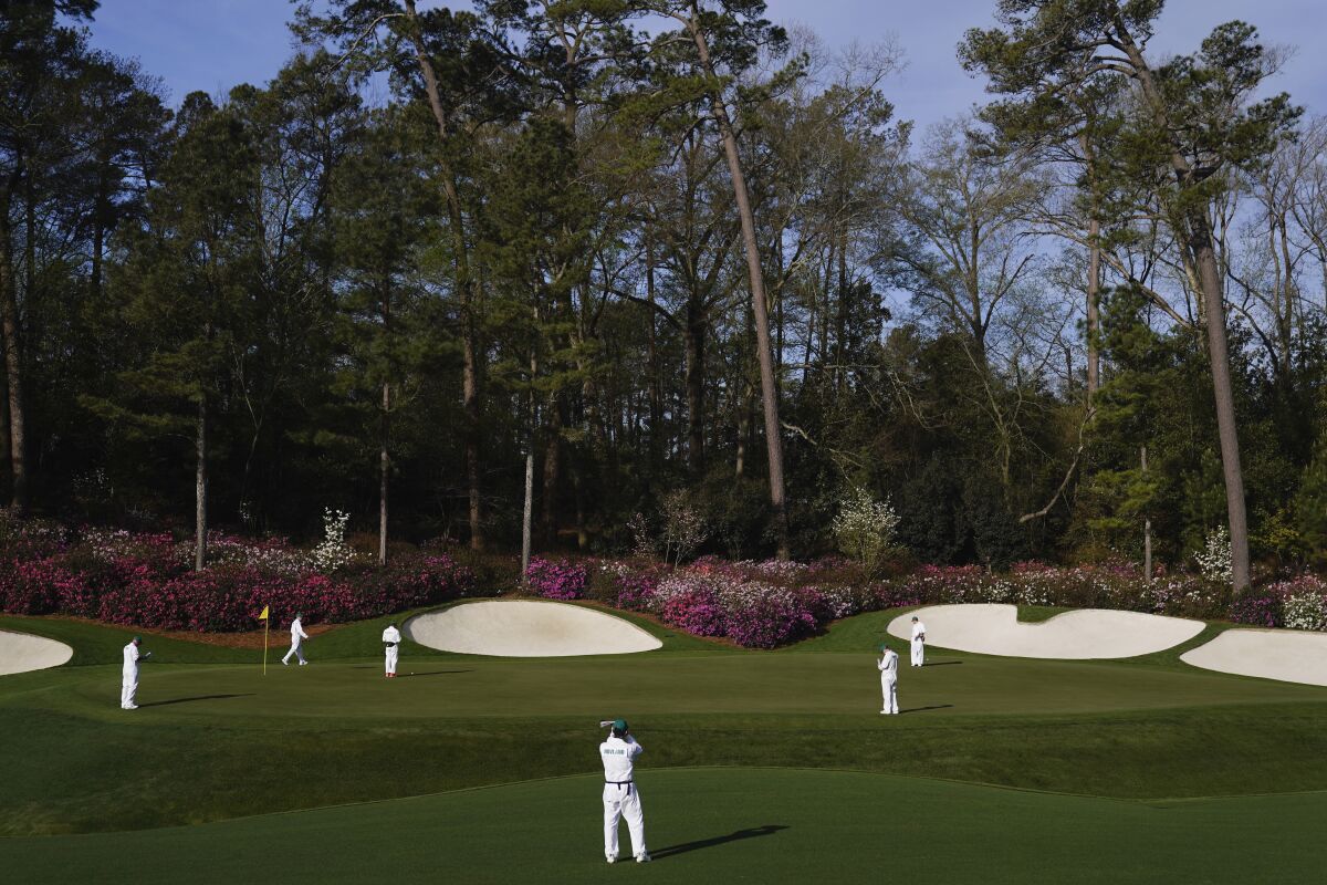 FILE - Masters' caddies examine the green on the 13th hole during a practice round for the Masters golf tournament on Monday, April 4, 2022, in Augusta, Ga. The Masters has no shortage of storylines at Augusta National. Tiger Woods returns after nearly two months. This will be only his third appearance against elite competition since last year's Masters. Rory McIlroy is in good form as he goes for the final leg of the career Grand Slam. And they share the stage with 18 players who most fans haven't see in more than nine months. (AP Photo/Jae C. Hong, File)