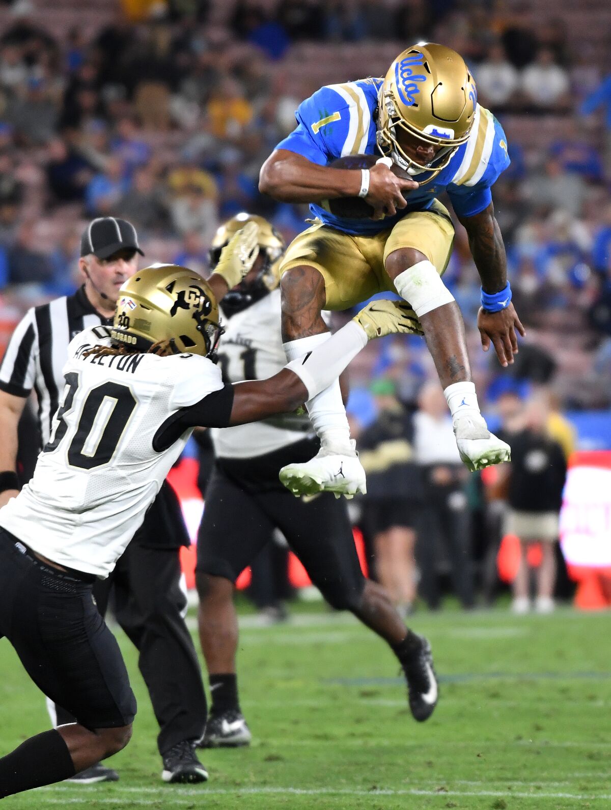 UCLA quarterback Dorian Thompson-Robinson leaps over Colorado safety Curtis Appleton during the third quarter Saturday.
