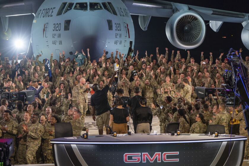 In this handout photo from the U.S. Air Force, American service members participate in a live broadcast with the hosts of Fox NFL Sunday during their Salute to Veterans broadcast, Nov. 13, 2022 at Al-Udeid Air Base in Qatar. As over a million World Cup fans fill stadiums with cheers and carry heady optimism through the streets of Doha, some 8,000 American troops are running air wars in Afghanistan, Iraq, Syria and other hotspots in the Middle East mere miles away. (U.S. Air Force/Airman 1st Class Andrew Britten, via AP)