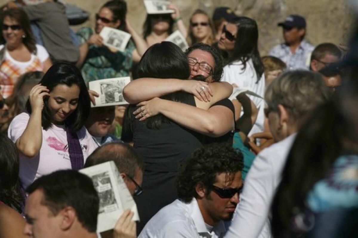 Sharon Aiken, whose husband, Christopher, was killed in the Metrolink train crash, is embraced at the start of a memorial ceremony at Stoney Point Park in Chatsworth to mark the one-year anniversary of the disaster, which killed 25 people and injured 135.