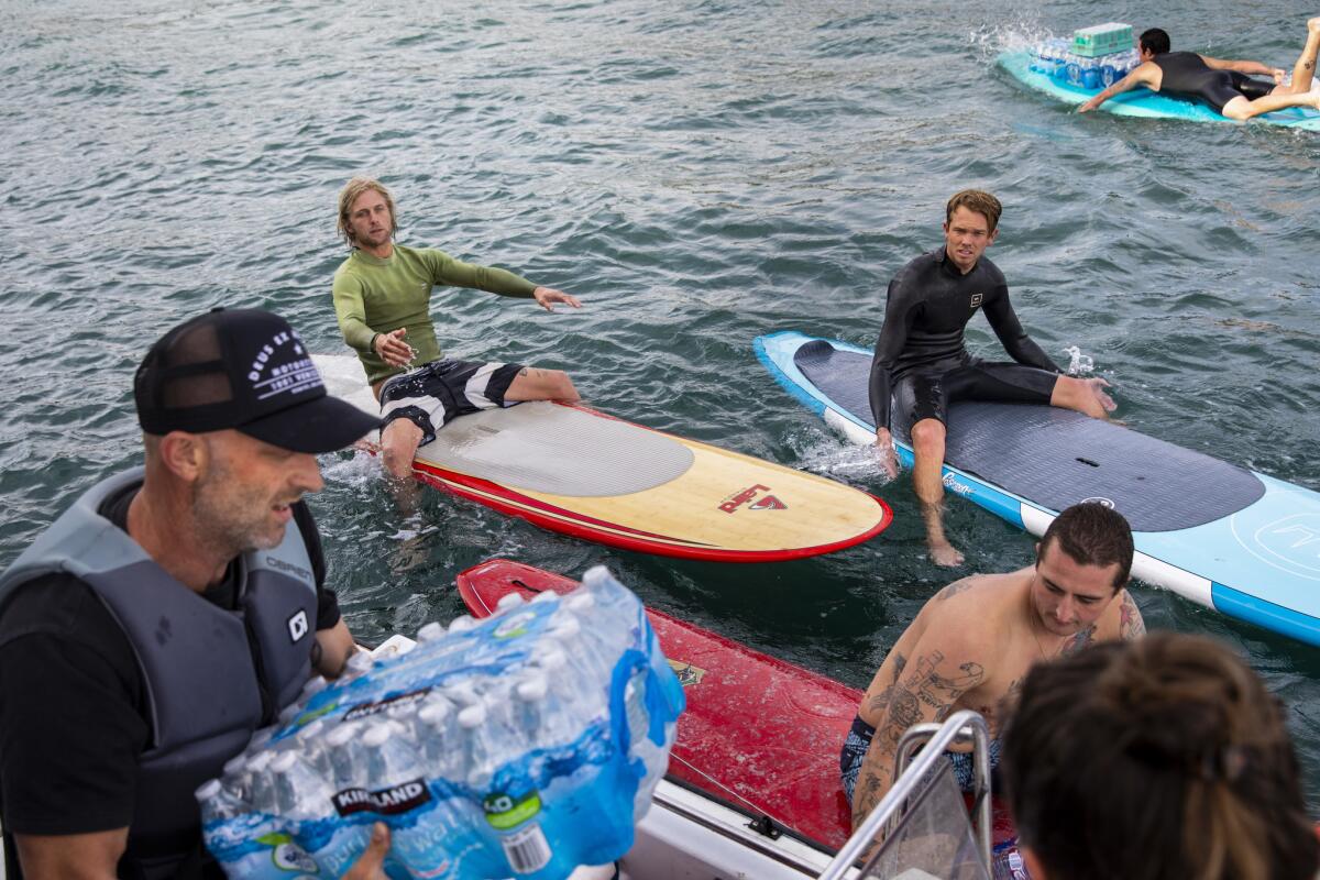 Volunteers hand off bottled water to surfers headed to Malibu's Paradise Cove to offer relief to those affected by the Woolsey fire.