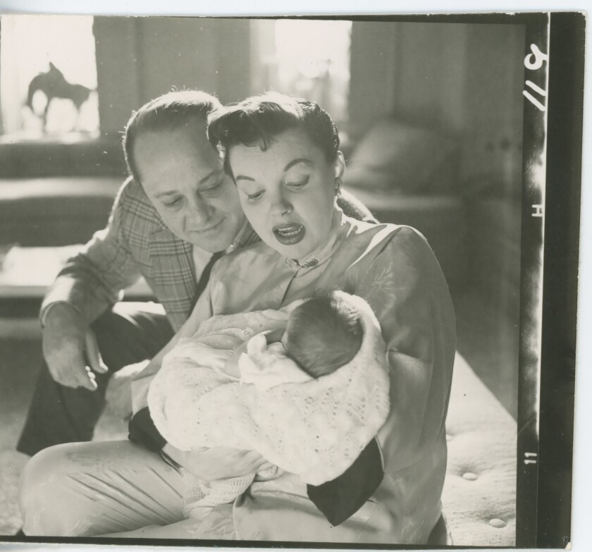 Judy Garland and then-husband Sid Luft look down at their newborn, swaddled in Garland's arms.