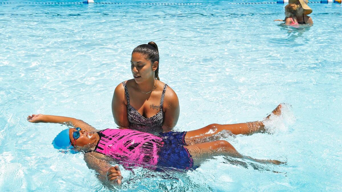 Rebecka Garcia, 9, with coaching from her mother, Irma Monterroso, works on her backstroke at Reseda Park Pool.