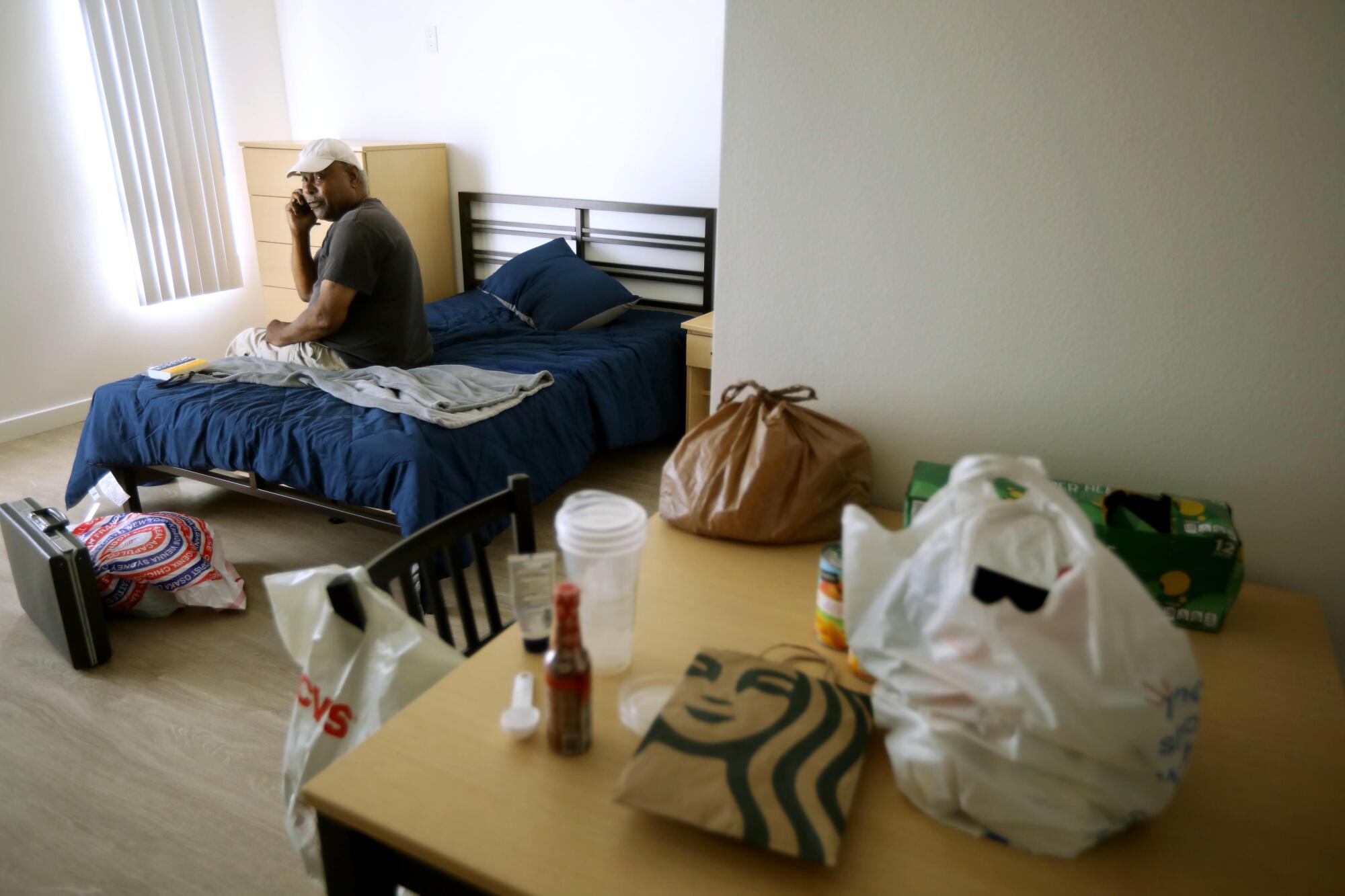 A man sits on his bed and reflects in his new apartment. 