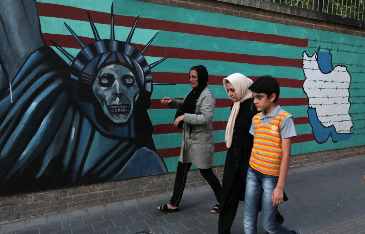 A family walks past anti-U.S. graffiti on the wall of the former U.S. Embassy in Tehran on July 14. President Hassan Rouhani told Iranians that "all our objectives" have been met by a nuclear deal agreed to after epic talks with world powers.