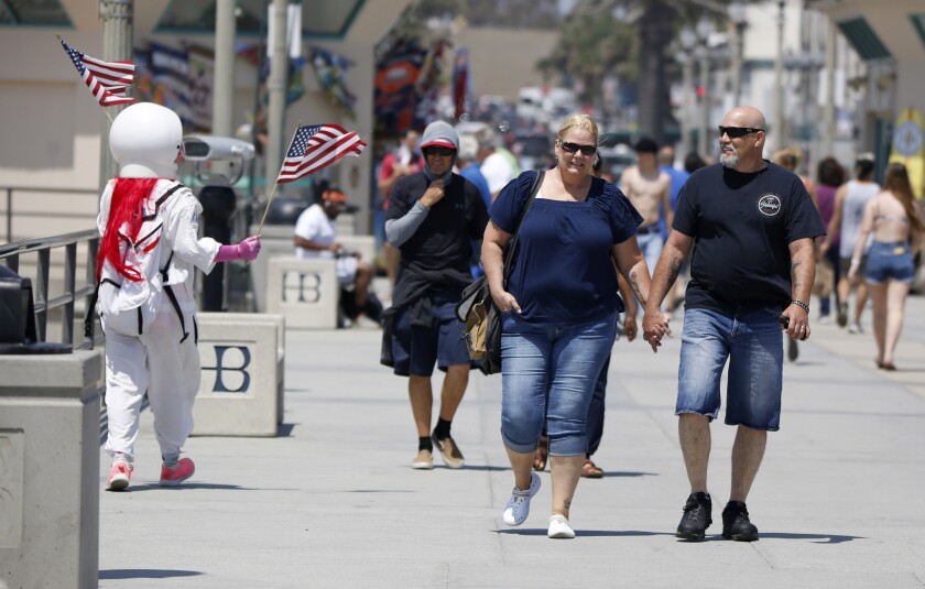 Angelina Franklin, 57, wears an astronaut costume as she waves American flags at the Huntington Beach Pier on Friday.