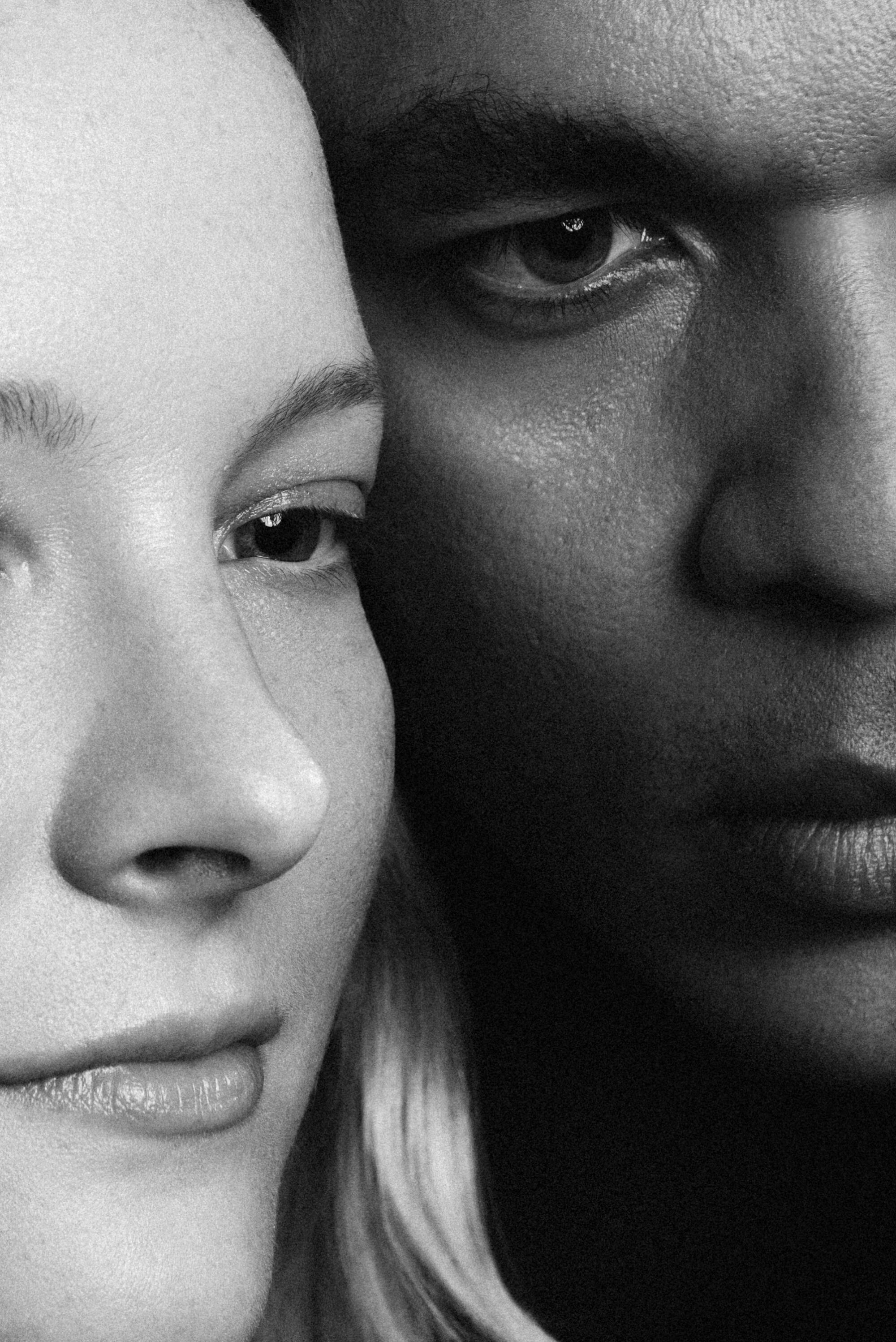 A close-up black-and-white photo of Morfydd Clark and Ismael Cruz Córdova, whose faces are half out of view.