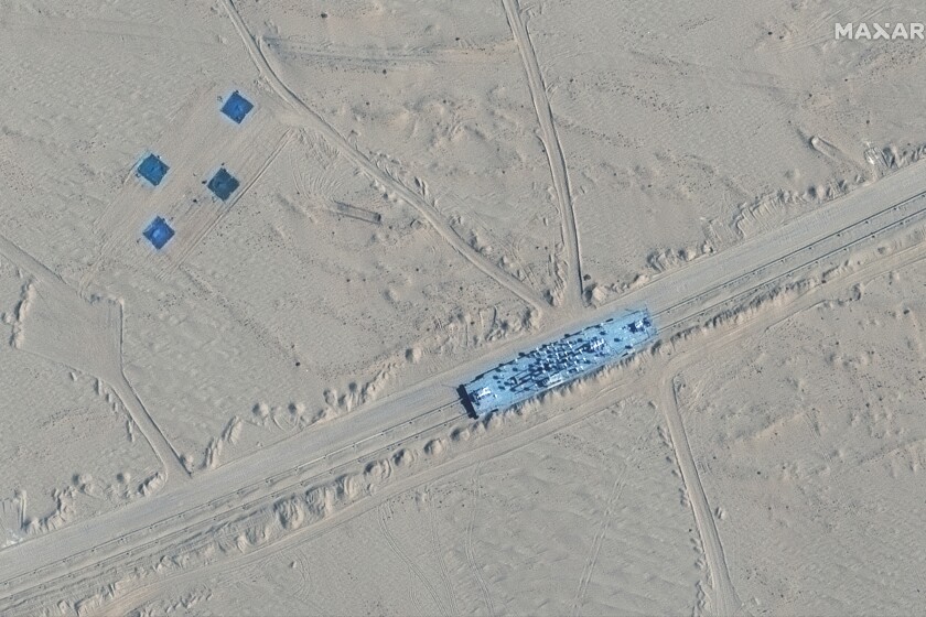 This satellite image provided by Maxar Technologies shows a building on rail tracks in Ruoqiang county, China, Wednesday, Oct. 20, 2021. Satellite images appear to show China has built mock-ups of U.S. Navy aircraft carriers and destroyers in its northwestern desert, such as one at center in this image, possibly as practice for a future naval clash as tensions rise between the nations. (Maxar Technologies via AP)