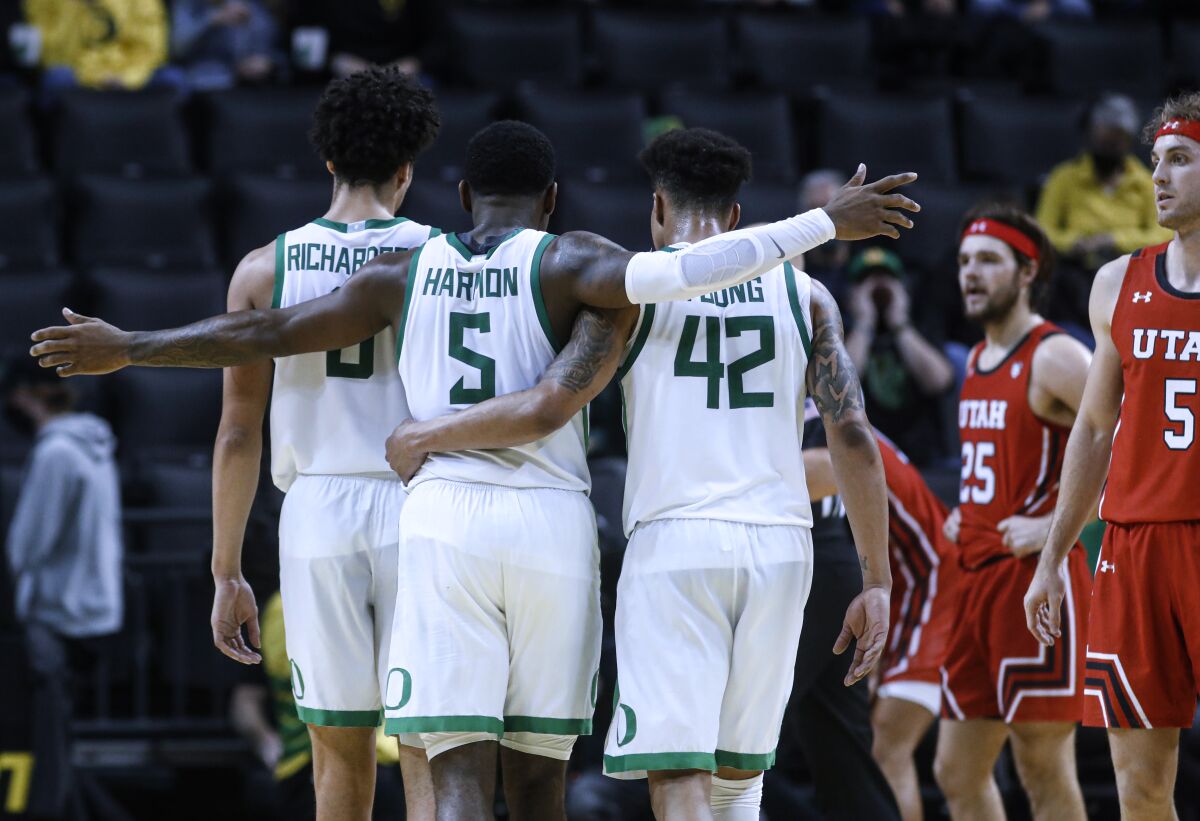 Oregon guard De'Vion Harmon (5) celebrates with Will Richardson (0) and Jacob Young (42) during the second half of the team's NCAA college basketball game against Utah in Eugene, Ore., Saturday, Jan. 1, 2022. (AP Photo/Thomas Boyd)