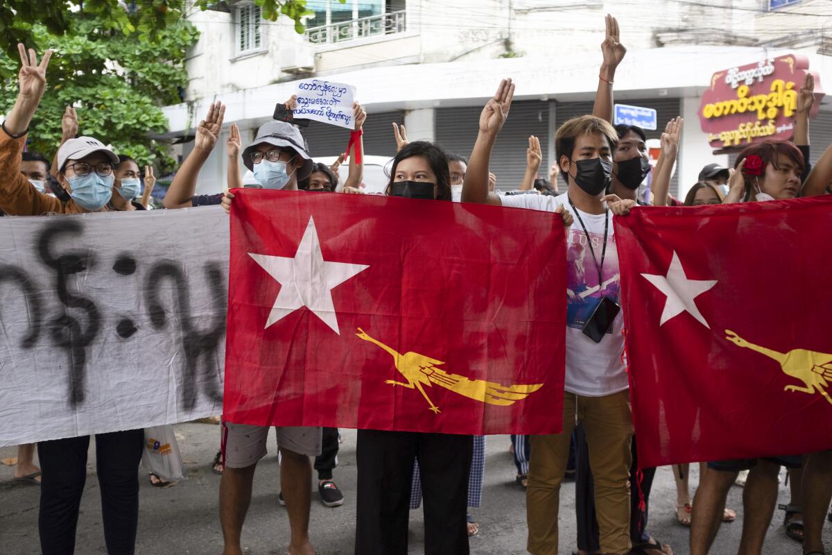 Protesters holding National League for Democracy (NLD) flags raise three-finger salutes during flash protests against the military coup at Bahan township in Yangon, Myanmar, Friday, June 25, 2021. (AP Photo)